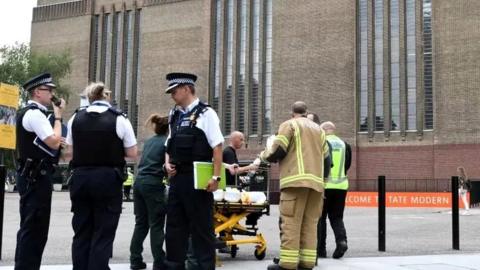 Police officers outside Tate Modern following boy's fall with stretcher behind