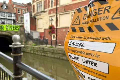 Local Democracy Reporting Service A fake 'warning' for sewage was placed in Lincoln on the River Witham as part of a protest