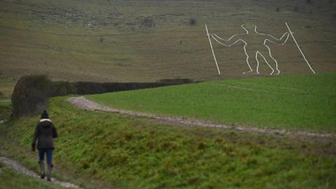 A person walking by the Long Man of Wilmington