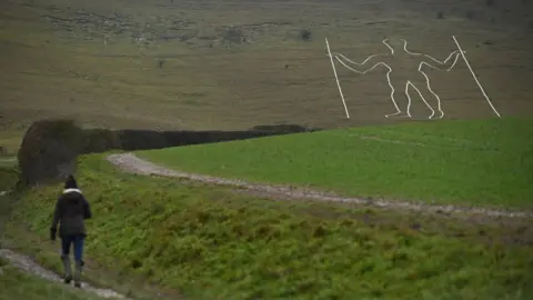 A person walking by the Long Man of Wilmington