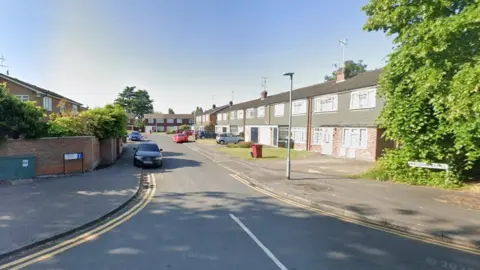 A row of terraced two-storey houses in Maldon Close. Cars are parked along the road and in driveways.