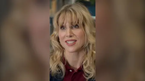 Amanda looks straight at the camera and smiles. She wears a burgundy polo shirt.