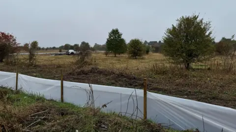 A field in Nottinghamshire with trees and a plastic barrier 