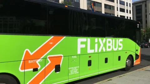 A FlixBus parked at the side of the road. It is bright green with orange arrows.