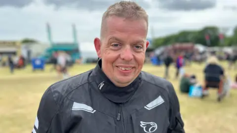 BBC Ciaran Donaghy is wearing a black biker jacket and has short fair hair.