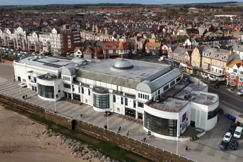 Getty Images An aerial view of Bridlington Spa in East Yorkshire. The white building with domed roof and large windows stands next to a sandy beach. Other buildings from the town are visible in the background.