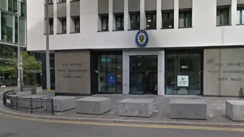 BBC The entrance to West Midlands Police headquarters is pictured. It has concrete blocks outside a stone and glass-fronted building with offices above.
