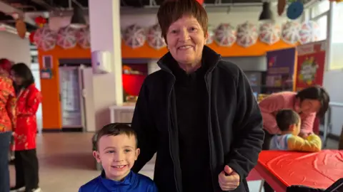 A child with dark hair smiling and a woman with dark hair smiling