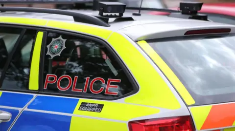 The back of a PSNI car. it is bright blue and yellow