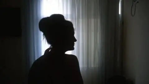 A silhouette of a woman. She cannot be identified. 