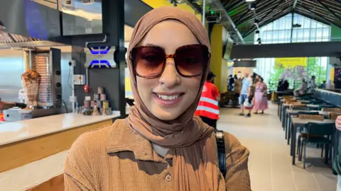 Woman smiling wearing sunglasses and a hijab.
