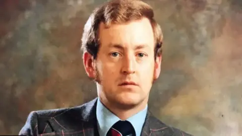 Handout Russell Causley wears a tweed suit and blue and red tie as stares unsmiling directly in the camera lens.