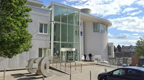 A light-coloured court building with a large floor to ceiling glass entrance way.