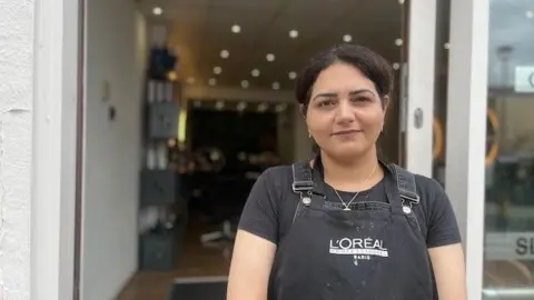 A woman in a L'Oreal apron stood outside a salon