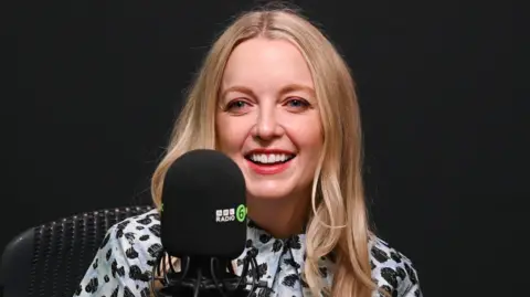 Lauren Laverne smiling in front of a 6 Music microphone in a radio studio