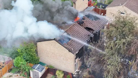 Two properties damaged by fire. Firefighters at the scene dealing with the incident.