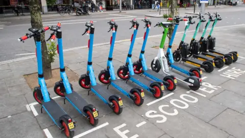 A row of e-scooters parked on a street.