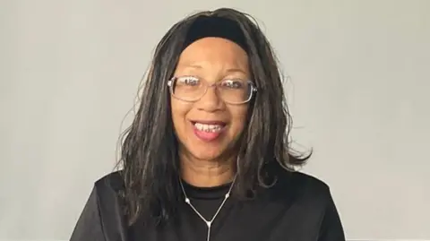 LDRS Yvonne Yew, who has shoulder length hair and tied back with a black headband, is wearing a black T-shirt and a necklace