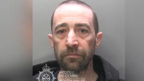 South Wales Police Mugshot of a man with a bald head and beard