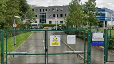 Secure green coloured gates of Moorside Primary School with the modern school building in the background