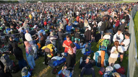 Thousands of people can be seen queueing up outside the festival in a bid to find the best camping spot. 