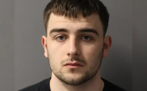 Metropolitan Police Lorik Lupqi police mugshot. He wears a dark top and looks at the camera
