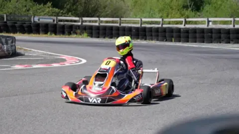 Noah drives his kart round the bend of a race track.