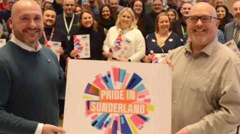 Two people holding up a Pride in Sunderland poster 