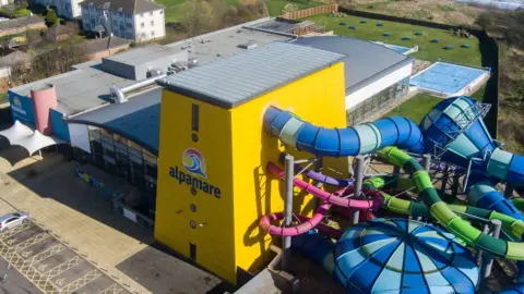 North Yorkshire Council An aerial shot of the Alpamare waterpark featuring a yellow main building, with blue, green and pink slides emerging.