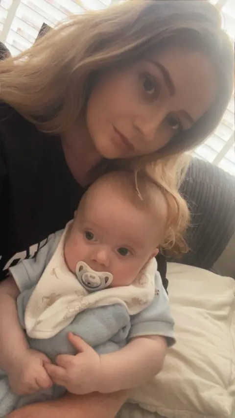 Hannah McCluskay Hannah McCluskay holds her six-month-old son. It is a selfie, she is wearing a black top and has long blonde hair, while her son is in a blue babygro with a white bib and a dummy in his mouth.