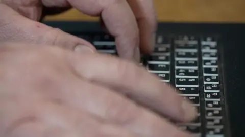 A man's fingers on a laptop keyboard