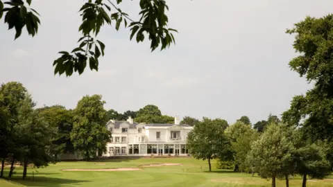 Double Image Photography Beeston Fields Golf Club  - it is a white building with grass in front of it surrounded by green trees