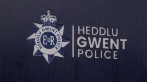 A blue sign bearing the words 'Heddlu, Gwent, Police' in white capitals.
