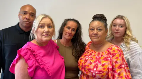 Kaine Fletcher's family. A man is pictured with four women and they are all looking at the camera.