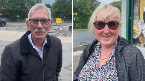 A side-by-side composite image of two people photographed on a street. On the left, an older man wearing glasses, a dark jacket and a light shirt stands near a road with traffic lights visible behind him. On the right, an older woman wearing sunglasses, a floral top and a dark jacket stands outside a shop front.