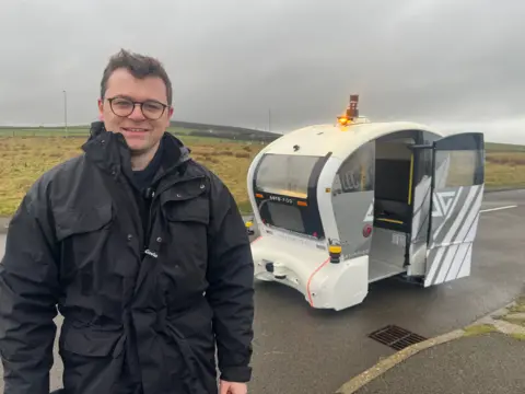 A man standing in front of a driverless vehicle