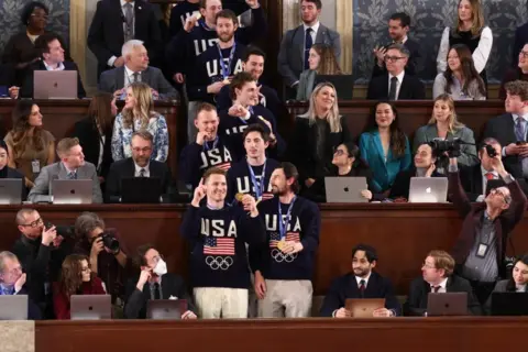 Reuters Hockey players hold their god medals while wearing navy sweaters with American flags on them