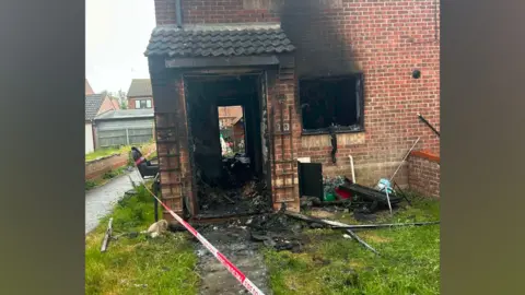 Brad Pruden A badly damaged home can be seen, with a doorway destroyed and smoke damage visible inside following a fire