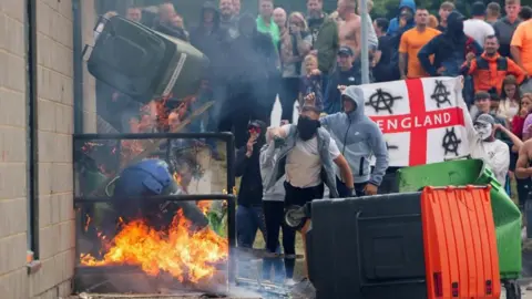 Reuters Protestors throw a garbage bin on fire outside a hotel in Rotherham, Britain, August 4, 2024