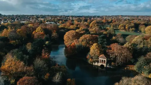 Drone shot of Birkenhead Park showing trees and its lake