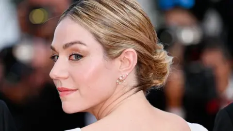 Getty Images Émilie Dequenne looking over her shoulder in front of a photographer bank at the Cannes Film Festival in 2023