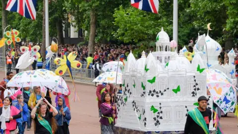 Same Sky A parade along London. Children holding artistic displays. 