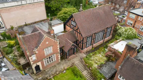 Historic England An aerial view of a red brick building with large windows, part of the building has exposed dark timber as part of its construction