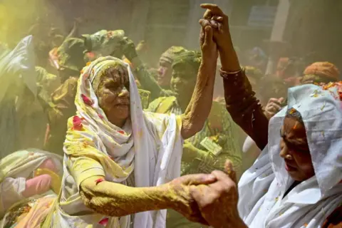 As viúvas da AFP manchadas de gulal (pó colorido), dançam enquanto celebram Holi, o Hindu Spring Festival of Colors, em um templo em Vrindavan em 12 de março de 2025.