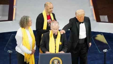 Reuters Keith Siegel, flanked by his wife Aviva Siegel and fellow former hostage Iair Horn, was comforted by President Donald Trump while he addressed the National Republican Congressional Committee (NRCC) dinner in Washington DC on 8 April 2025