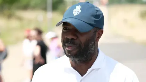 Omosuyi Fred-Omojole, who is wearing a green cap and a white tennis shirt