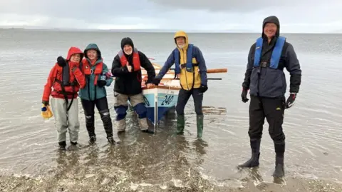 A group of people stand around a boat