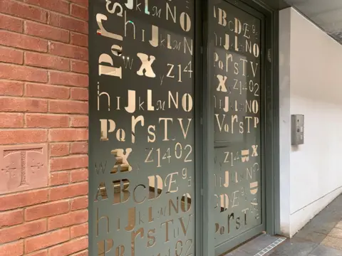 A metal doorway with a large number of numbers and letters carved into it