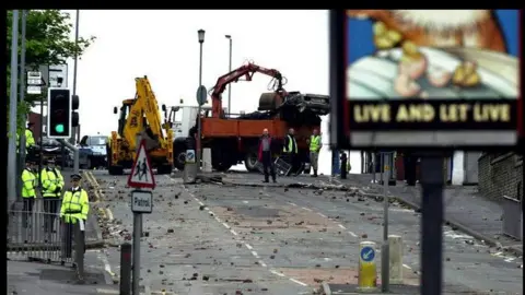 PA Media Debris on an empty road after a riot near a pub where there is sign for it's name "Live And Let Live"