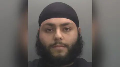 A police custody shot of a bearded man 